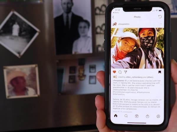 Photo of a smart phone showing a social media post with a photo of two women wearing hats and bandanas, with other vintage photos surrounding the phone