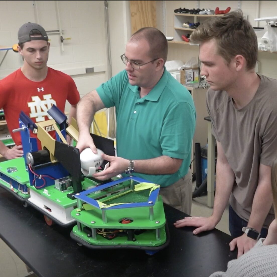 Professor Craig Goehler demonstrates a football playing robot to his engineering students in the lab