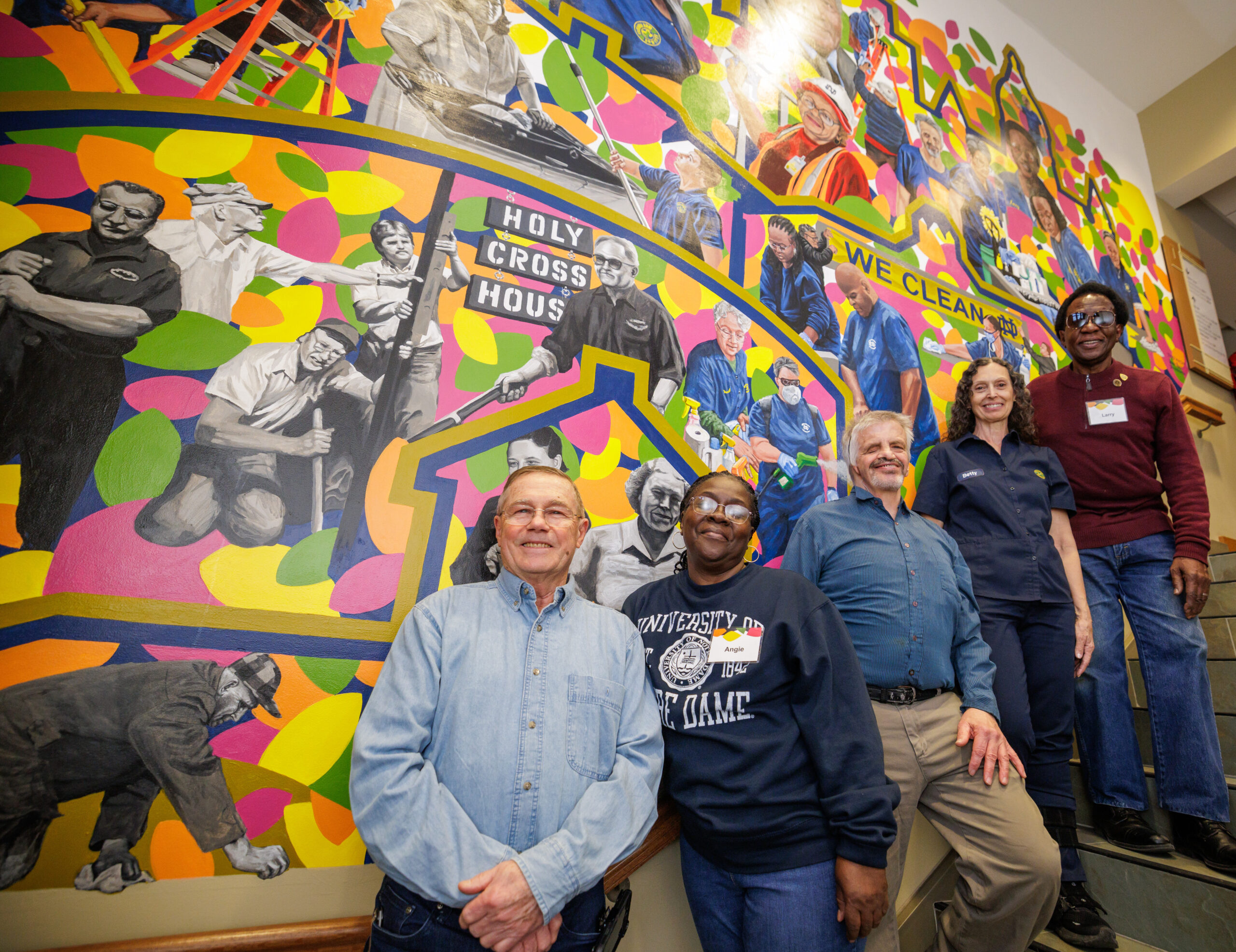 Building Services workers Bruce Haney (left), Angela Hubbard, James Nissley, Betty Wildrick, and Larry Robinson stand in front of their images in mural