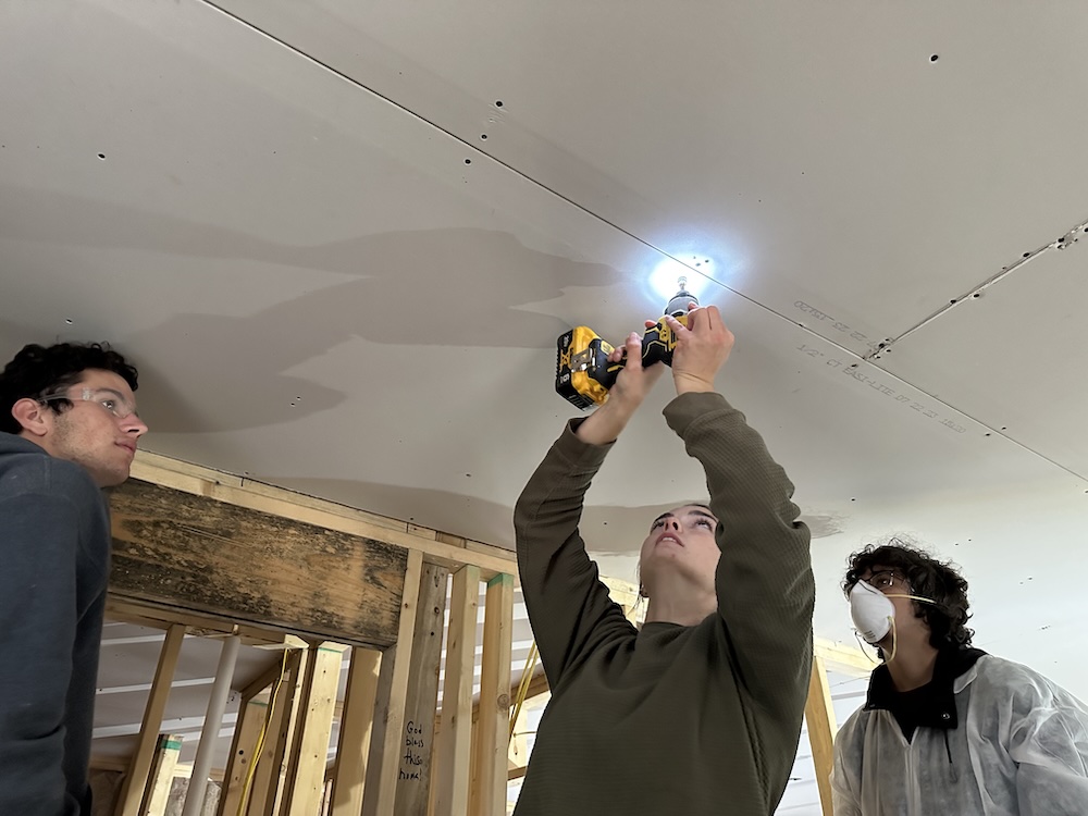 Student uses a drill on the ceiling of a home in Appalachia