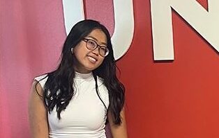 Two students stand in front of Unite sign on red wall