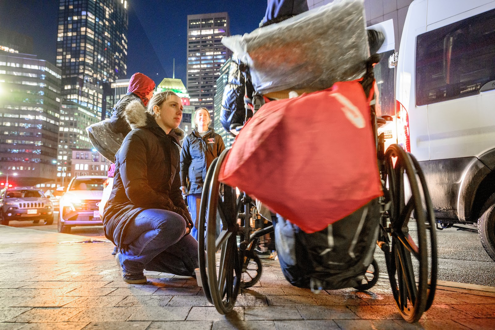 Camille Keehan ’26 crouches by woman in wheelchair on street in Boston